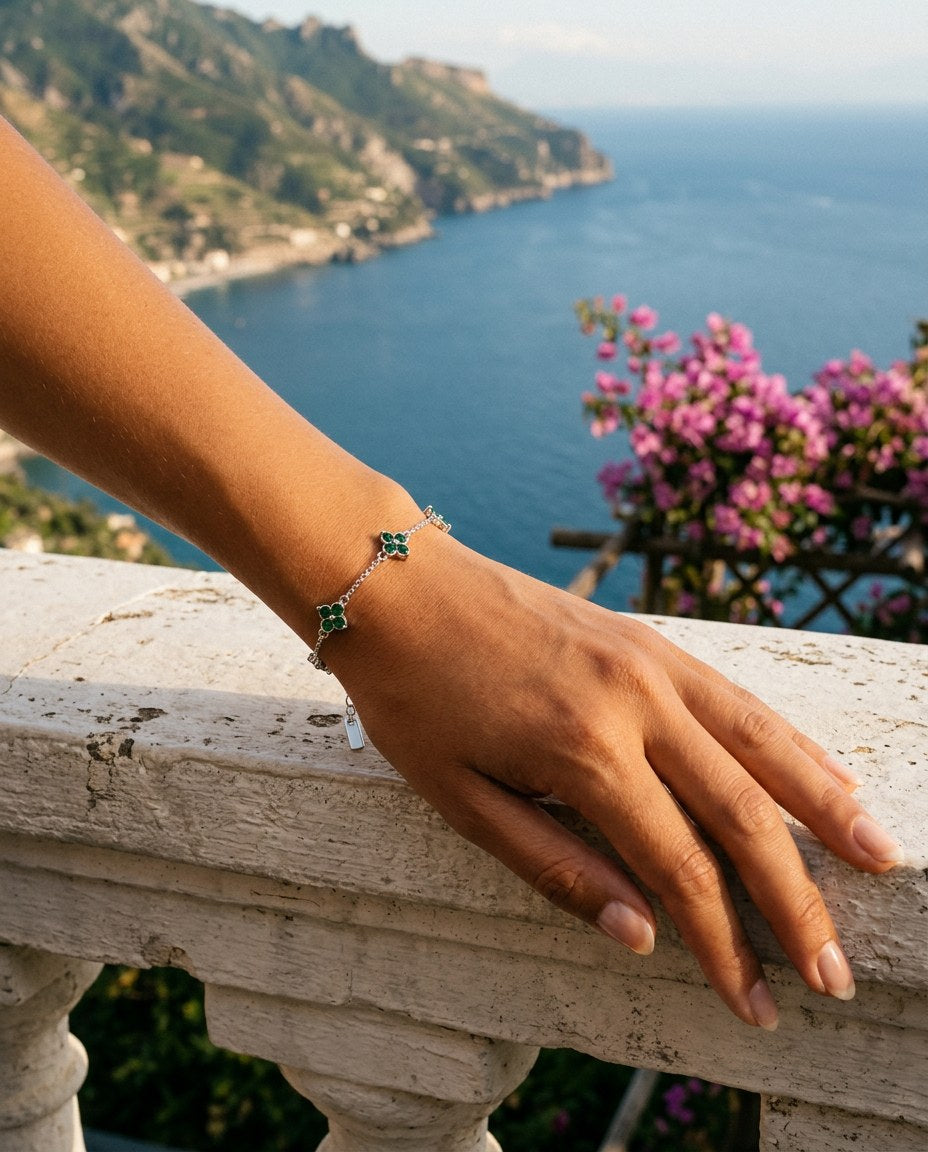 Handgelenk mit The Fortuna Bracelet auf einer Steinbalustrade mit Bougainvillea und Meer